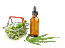 A bottle of cannabis oil extracts and green marijuana leaves in a mini basket isolated on a white background. Medical cannabis plantation and business concept photo