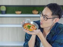 Young man's wearing glasses smiling showing the fried egg with colorful toppings served on a pan. photo