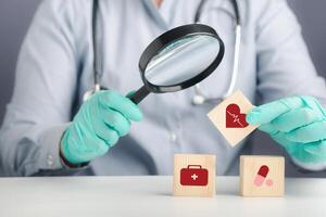 A doctor holding wooden blocks with icons of health and doctors in his hands. Close-up photo. Space for text. Concept of doctor work in maintaining human health photo