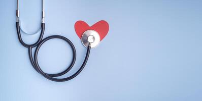 A stethoscope and red paper a heart shape isolated on a light blue background. Close-up photo. Top view. Flat lay with Space for text. Healthcare and medicine concept photo