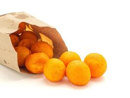 Fried small sweet potato balls outside of a paper bag on white background. Snack unhealthy concept photo