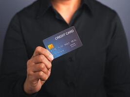 Businessman holding a mockup blue credit card while standing in a studio with copy space for text. Close-up photo. Money and business concept photo