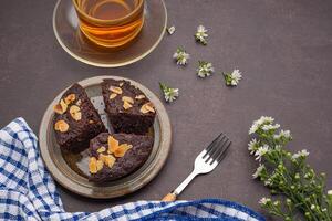 Pieces of fresh brownies on a plate with teacup. Side view. Delicious chocolate pie. Dessert and relaxation concept photo