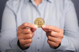Investor guy showing a bitcoin golden coin with a gray background. Close-up photo. Space for text. Virtual cryptocurrency and future money concept photo