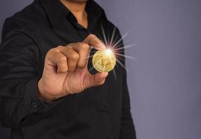 Investor guy showing a bitcoin golden coin with effect sunlight. Close-up photo. Space for text. Virtual cryptocurrency and future money concept photo