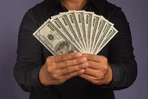 Businessman hand holding of US banknotes while standing in a studio. Close-up photo. Business and finance concept photo