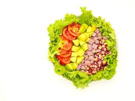Top view of green lettuce salad with fresh mixed purple corn, purple yams, avocado, and tomatoes on a dish placed on white background. Space for text. Healthy foods concept. Clipping path photo