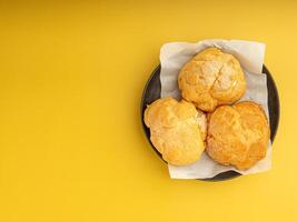 Top view of choux cream on a plate placed on a yellow background. Space for text. Concept of dessert and relaxation photo