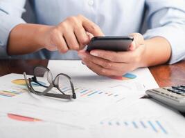 Close-up of hand holding a smartphone with the chart, graph report for the business. Space for text. Business, finance, planning, and communication concept photo