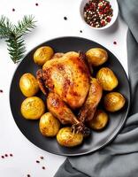 Creative food concept. Roasted chicken with potatoes on dark plate. Close-up. Top-view. against a white background.-Roasted chicken It's a golden brown color that's freshly baked. mock up. photo