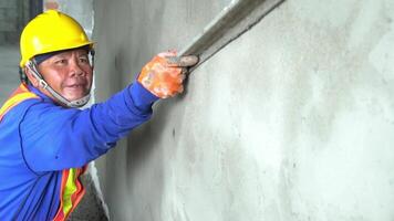 Asian worker uses tools to smooth plaster on a wall Home construction and home decoration archive in architecture video