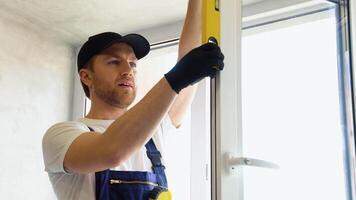 Worker in uniform installing new plastic pvc window video