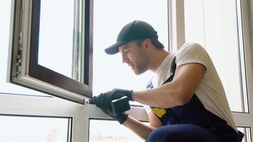 Workman in overalls installing pvc window with screwdriver video