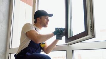 Workman in overalls installing pvc window with screwdriver video