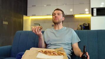Portrait of a Handsome Man Sitting on a Couch at Home at Night, Watching Comedy Series on TV And Eats Pizza. Man Good Fun Watching Movie video