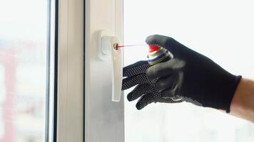 Close up of man applying lubricate oil for lock of plastic window. Maintenance checks of pvc windows. Handle with a lock on the window video