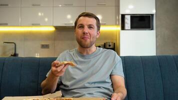 Portrait of a Handsome Man Sitting on a Couch at Home at Night, Watching Comedy Series on TV And Eats Pizza. Man Good Fun Watching Movie video