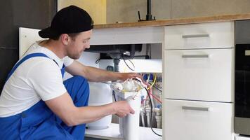 Repairman installing water filter cartridges in a kitchen. Installation of reverse osmosis water purification system video