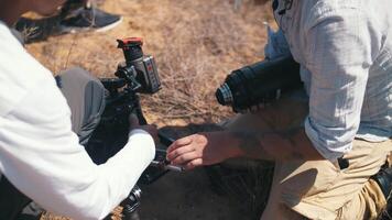 Installing a movie lens on a camera. Camera man install lens in camera before filming in steppe. High quality 4k footage video