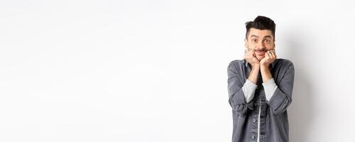 Cute young man with moustache smiling and looking dreamy at camera, gazing at something beautiful, admire true beauty, standing on white background photo