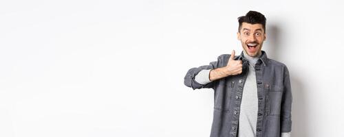 Well done, very good. Excited handsome guy praising nice work, showing thumb up and smiling happy, approve awesome choice, standing on white background photo