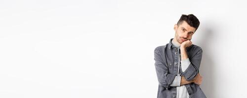 Bored and reluctant stylish guy look at camera without emotions, attend boring meeting, standing on white background photo