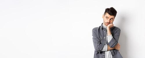 Gloomy thoughtful man looking aside, thinking or space out, staring at empty space bored, standing on white background photo