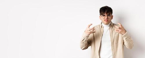 Portrait of annoyed and mad guy wants to strangle someone, grimacing from hatred and clench arms, standing bothered on white background photo