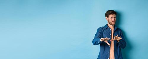 Guy cringe from something awful and nasty, refusing from bad ofer, looking disgusted, standing on blue background photo