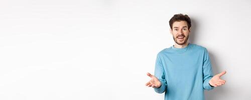 Handsome young man feeling happy for you, pointing hands at camera and praising good work, congratulations gesture, standing over white background photo