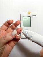 Measurement of blood sugar levels using a glucose meter with a mock-up. Piercing a finger to draw blood photo