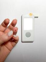 Measurement of blood sugar levels using a glucose meter with a mock-up. Piercing a finger to draw blood photo