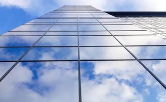 View of a modern glass skyscraper. Reflection of a cloudy blue sky in a glass skyscraper photo
