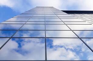 View of a modern glass skyscraper. Reflection of a cloudy blue sky in a glass skyscraper photo