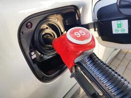 Filling the car with gasoline. Insert the red gun into the tank of the car for refueling. The process of refueling the car with fuel photo
