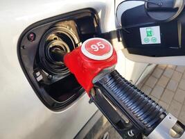 Filling the car with gasoline. Insert the red gun into the tank of the car for refueling. The process of refueling the car with fuel photo