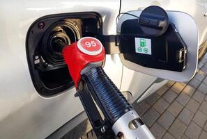 Filling the car with gasoline. Insert the red gun into the tank of the car for refueling. The process of refueling the car with fuel photo