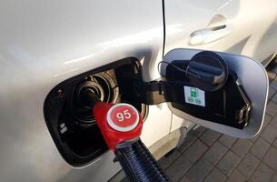 Filling the car with gasoline. Insert the red gun into the tank of the car for refueling. The process of refueling the car with fuel photo
