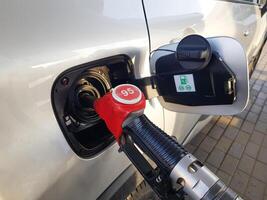 Filling the car with gasoline. Insert the red gun into the tank of the car for refueling. The process of refueling the car with fuel photo