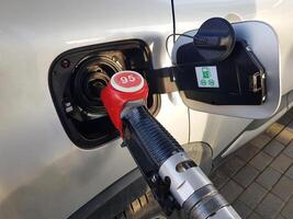 Filling the car with gasoline. Insert the red gun into the tank of the car for refueling. The process of refueling the car with fuel photo