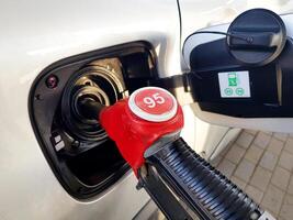 Filling the car with gasoline. Insert the red gun into the tank of the car for refueling. The process of refueling the car with fuel photo