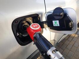 Filling the car with gasoline. Insert the red gun into the tank of the car for refueling. The process of refueling the car with fuel photo