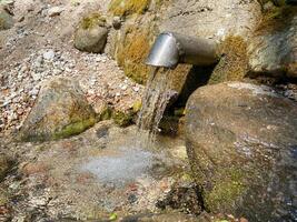 A fresh and cool spring flows from the ground. Cool and delicious spring water. Natural underground water source photo