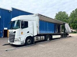 Cargo transportation of screws in wooden and metal boxes in a semi-trailer truck. Side loading of bolts photo