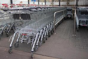 Metal grocery carts stand in a store parking bay photo