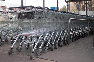 Metal grocery carts stand in a store parking bay photo