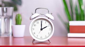 Classic white clock on a table. The clock hand points at 2, 14 close up photo