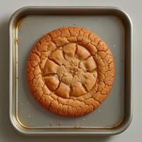 A Golden Brown Cookie With a Sunburst Pattern on a Baking Sheet photo