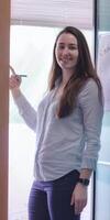 Young Woman Presenting Information on Glass Board in Office Setting photo
