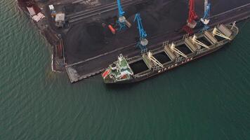 Drone view of cranes loading coal in the port on a bulk carrier video